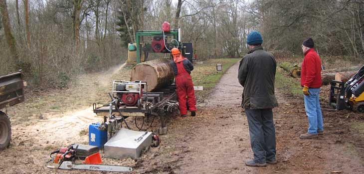 Mobile band saw mill located along side Waste Drive. Alistair Williams operating mill with volunteers Geoff Fisher and Laurie Moir waiting to lift off cut timber.