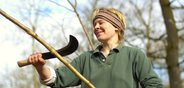 Person making a beanpole from coppiced material