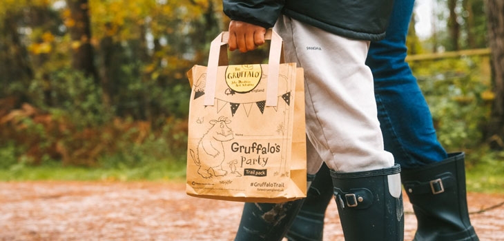 A person holding a paper bag with the Gruffalo printed on it. 