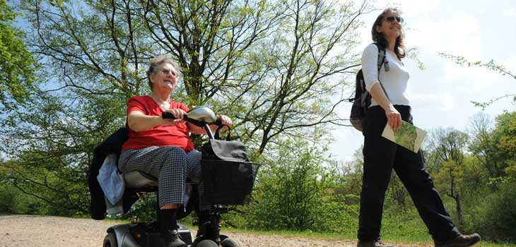 A woman walking and an older woman riding a scooter.